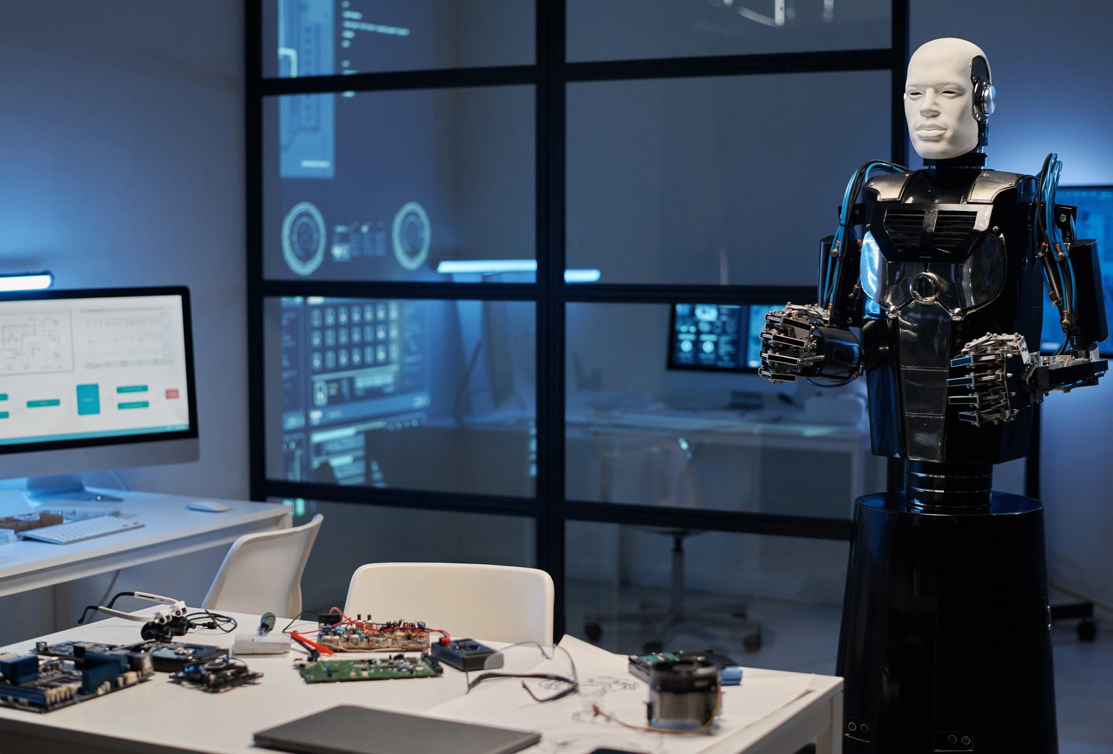 A humanoid robot standing in a glass-walled tech lab