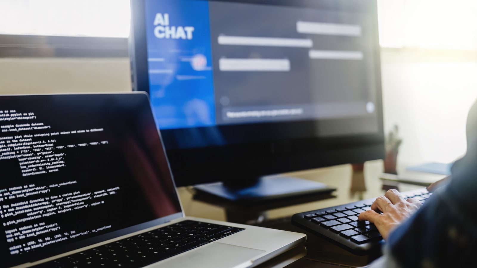 A person typing at a desk with an AI chat window on the monitor